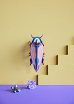 Studio Roof Violet Click Beetle hung up on a yellow painted wall