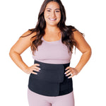 Lola & Lykke Core Restore Postpartum Belly Band. A person wearing a pink outfit, and the belly band 