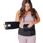A person wearing a pink outfit, showing how to put on the Lola & Lykke Core Restore Postpartum Belly Band