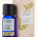Tea tree pure essential oil in a blue glass bottle in front of a decorative pink cardboard box.