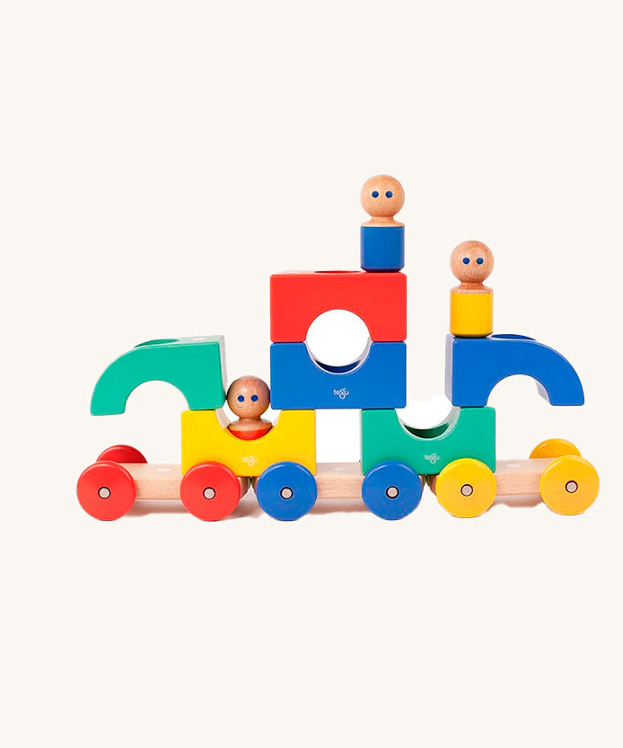 Tegu Big Top Magnetic Tram toy pictured on a plain background. The blocks have been stacked on top of each other with one of the  wooden dollies placed on top. 
