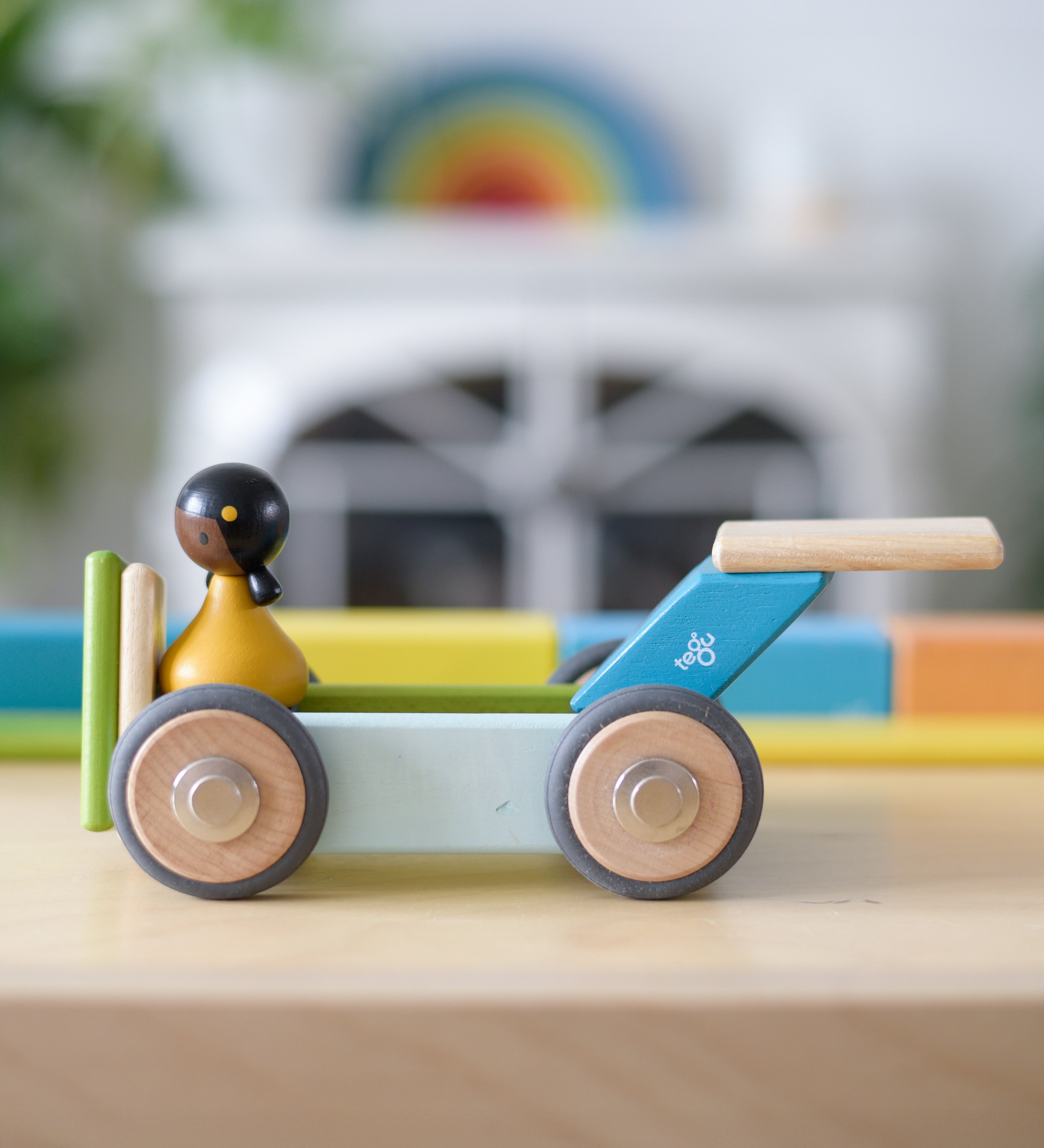 Tegu wheels made into a vehicle with other magnetic wooden pieces and a Clique figure on top