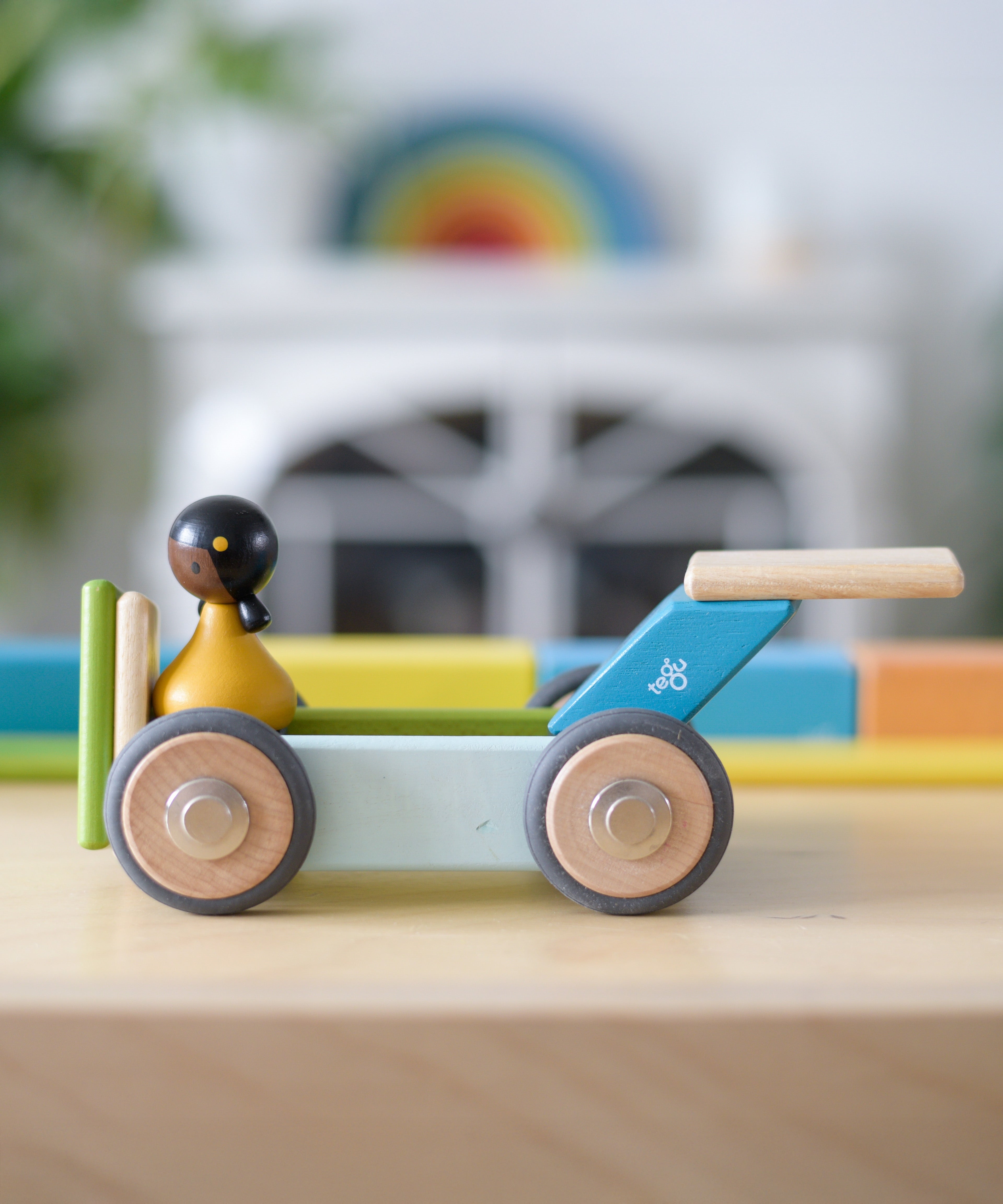 Tegu wheels made into a vehicle with other magnetic wooden pieces and a Clique figure on top