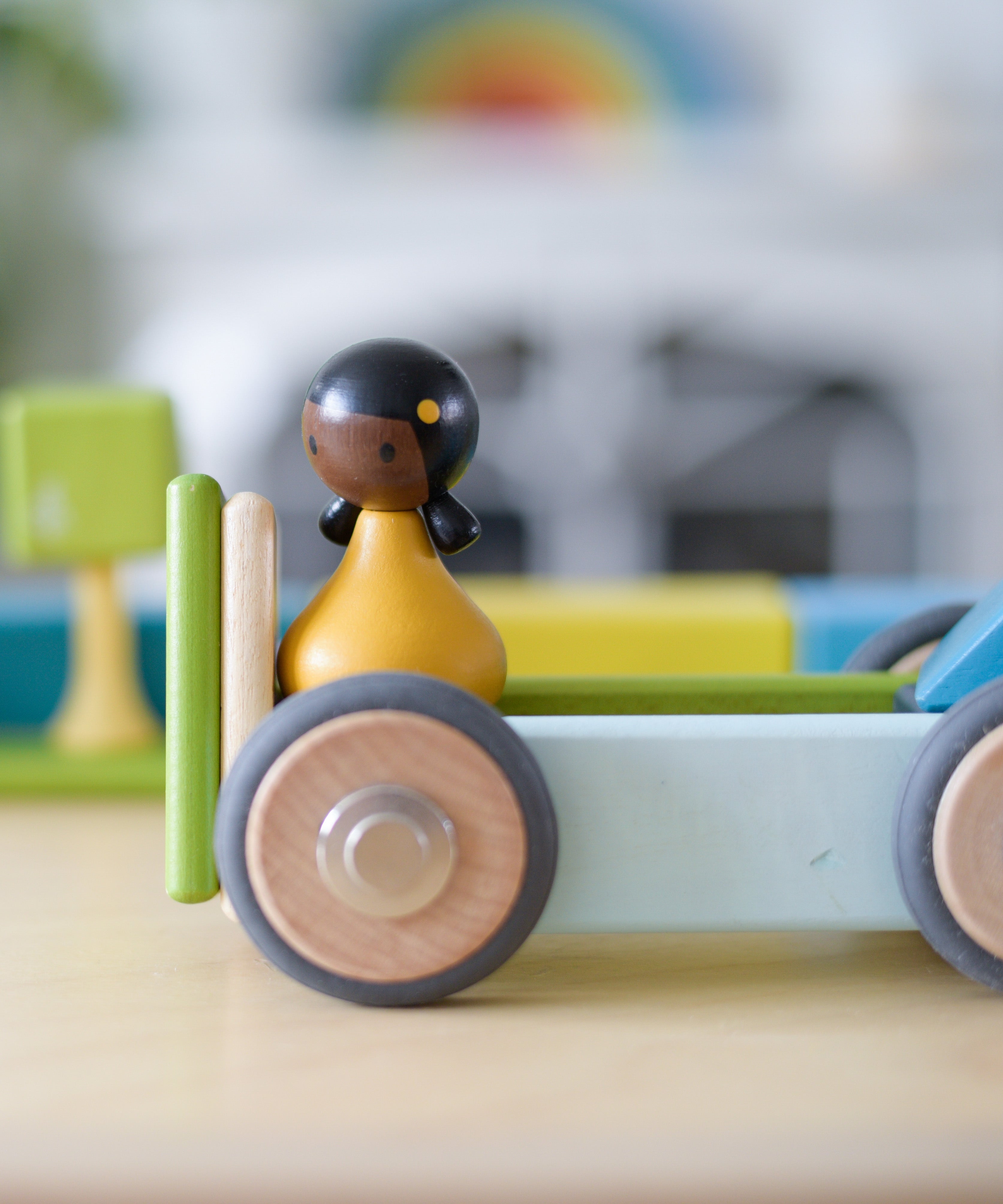 A close up of the Tegu wheels made into a vehicle with other magnetic pieces and a Clique figure on top