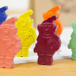 Close up of the Crayon Bug elf crayons stood on a wooden table and a colouring book