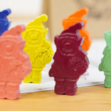 Close up of the Crayon Bug elf crayons stood on a wooden table and a colouring book