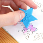 Close up of a hand holding a blue Crayon Bug festive crayon over a colouring book picture