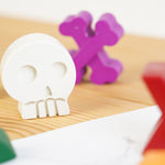 Close up of a crayon bug white crayon skull on a wooden work top next to some crayon bug pirate treasure crayons