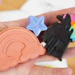 Close up of a hand holding some crayon bug unicorn dreams handmade coloured crayons