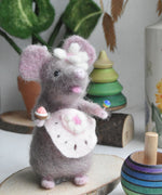 A felted mouse figure wearing a pink apron and holding a cake and lollypop in it's hands. The figure has been created using The Makerss Candy Mouse Needle Felt Craft Kit.