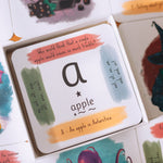 The Phive Enchanting Learning Phonics & Storytelling Cards - Set 1 card laid out with the box on top with a card with the letter a for apple on the top