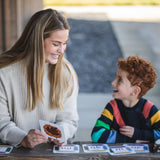An adult sitting next to a child with a The Phive Enchanting Learning Phonics & Storytelling Card Set laid out in front of them