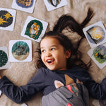 Child lying down surrounded by cards from the The Phive Enchanting Learning Phonics & Storytelling Cards  Set 2