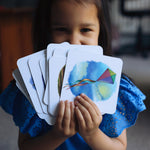 Child holding the cards from the The Phive Enchanting Learning Phonics & Storytelling Cards - Set 3 in a fan front of their face