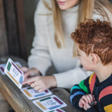 An adult sitting next to a child with a The Phive Enchanting Learning Phonics & Storytelling Card Set laid out in front of them