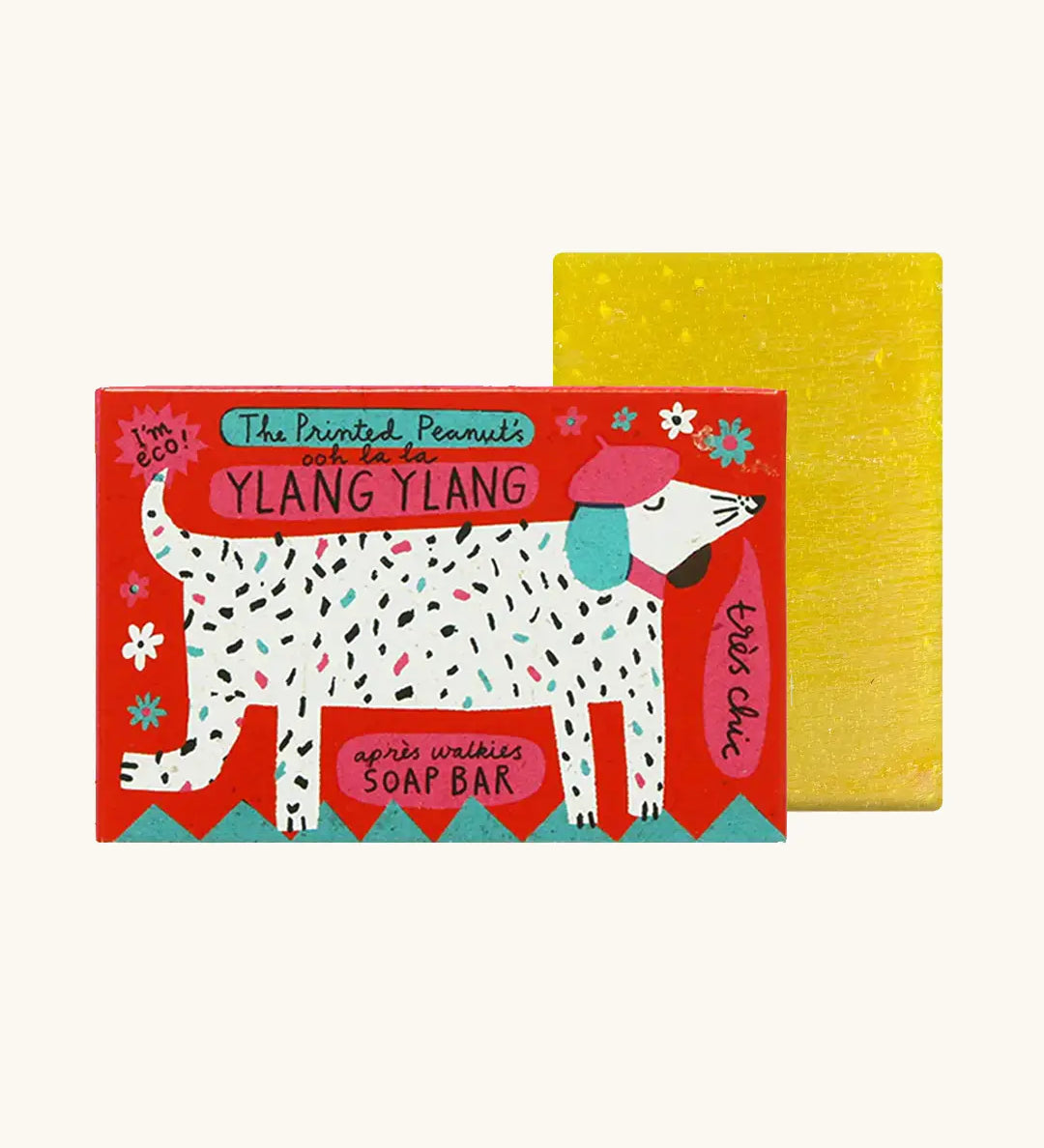 The Printed Peanut ylang ylang natural handmade soap bar standing next to  it's decorative cardboard box showing a white dog wearing a beret