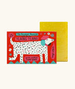 The Printed Peanut ylang ylang natural handmade soap bar standing next to  it's decorative cardboard box showing a white dog wearing a beret