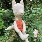 Tobe the hempions fox toy placed on greenery outdoors. 