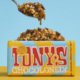 A bar Tony's Chocolonely Fairtrade Milk Rice Crispy Caramel chocolate with a pile of chocolate caramel covered crispies in the background. 