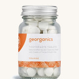 A jar of the Georganics orange toothpaste tablets on a cream background
