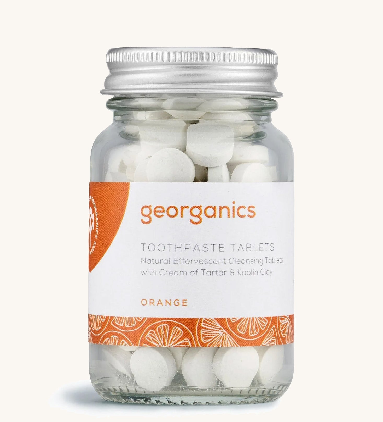 A jar of the Georganics orange toothpaste tablets on a cream background