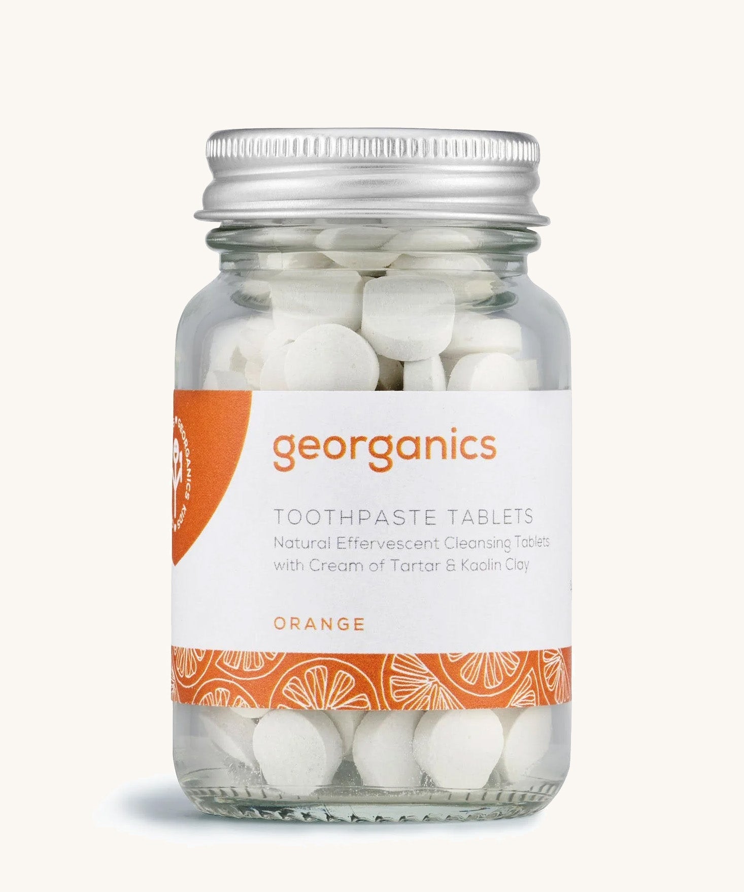 A jar of the Georganics orange toothpaste tablets on a cream background