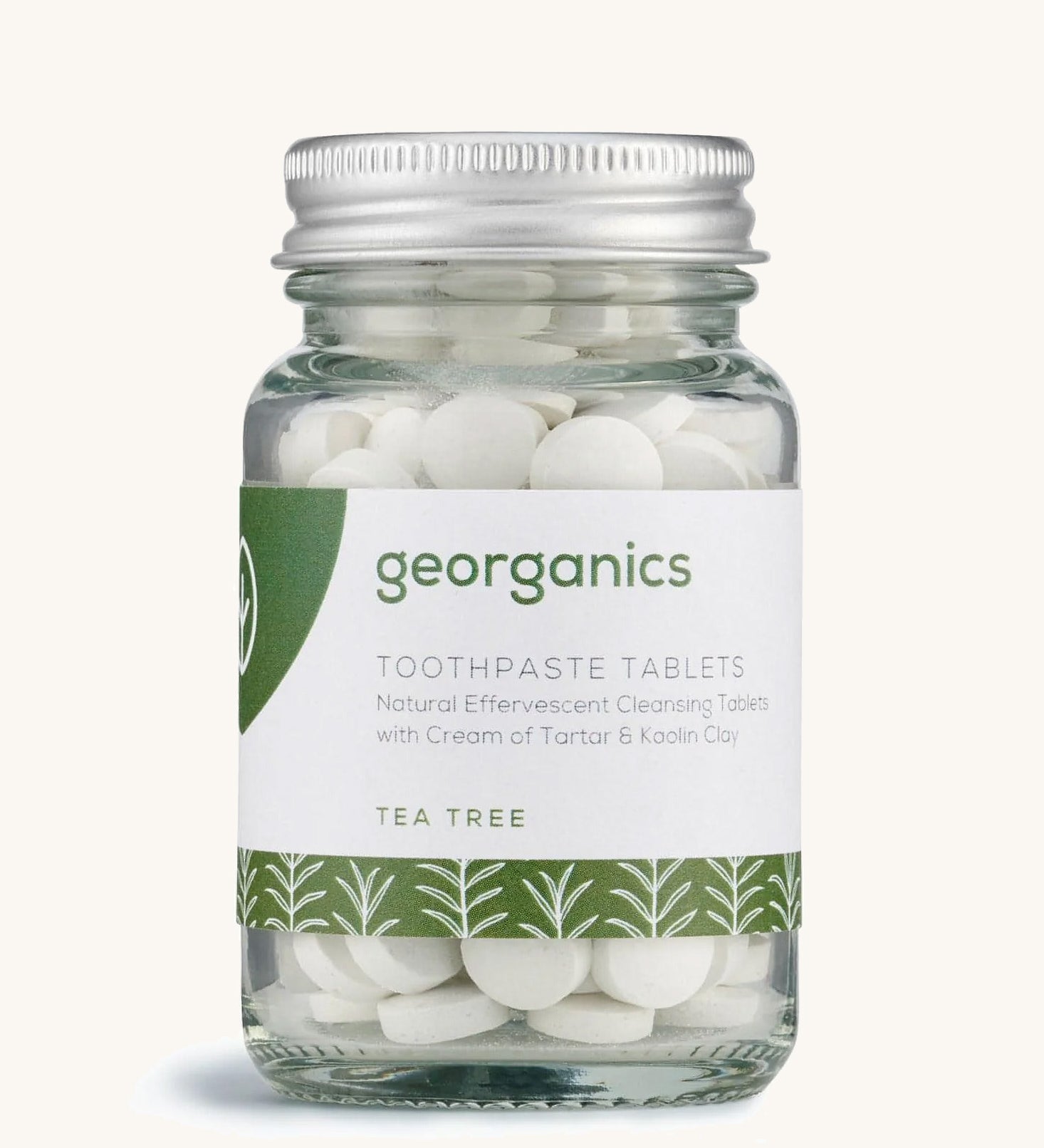 A jar of the Georganics tea tree toothpaste tablets on a cream background.
