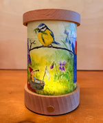 Spring Toverlux lantern shade with gnome tales artwork by Mhairi Hellbrandt  featuring a blue tit bird displayed in a lit lantern.