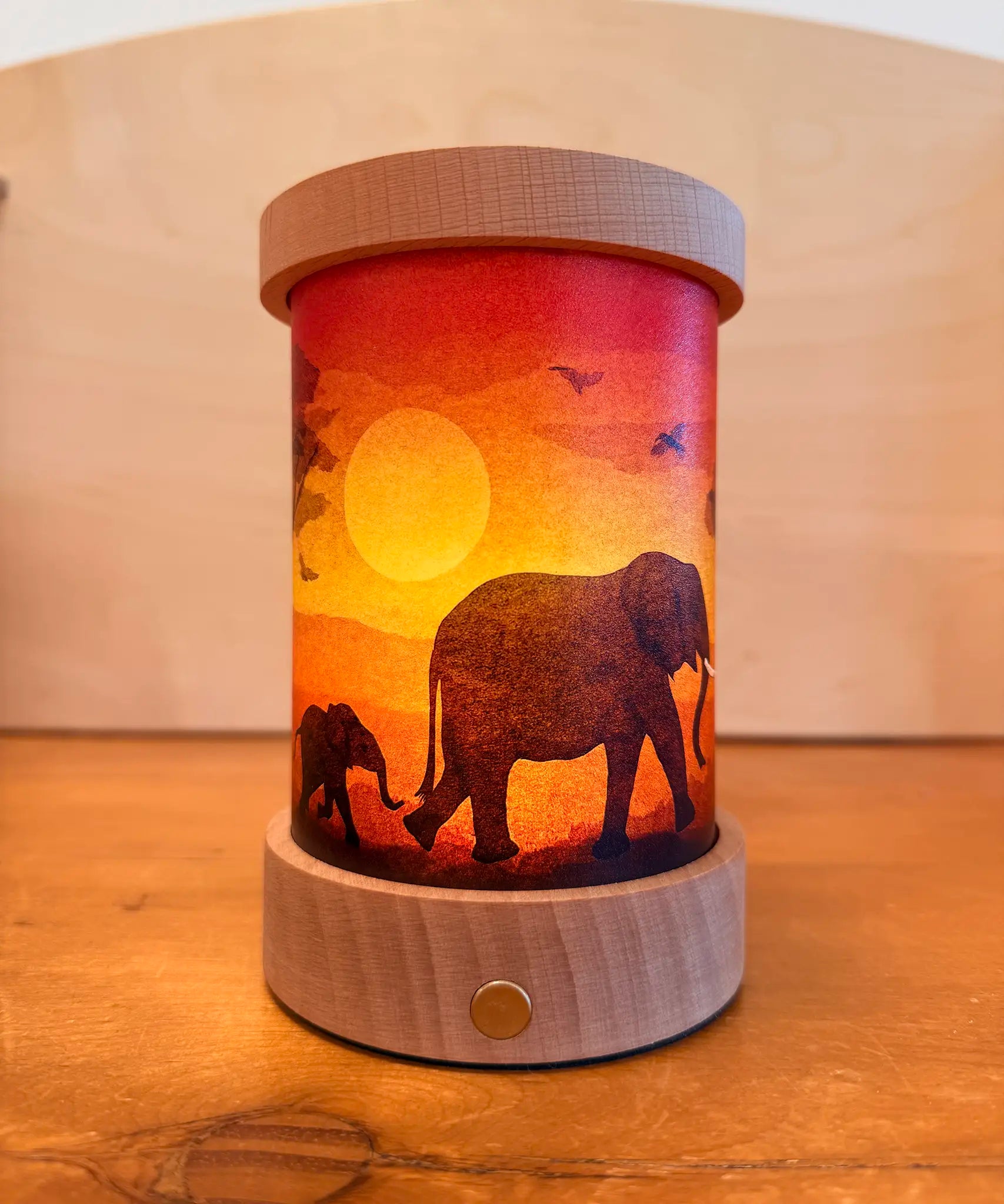 Toverlux Lantern shade by Vogel Geluk, transparency artworks of fauna  featuring elephants walking in a sunset. The shade has been displayed in a lit lantern. 