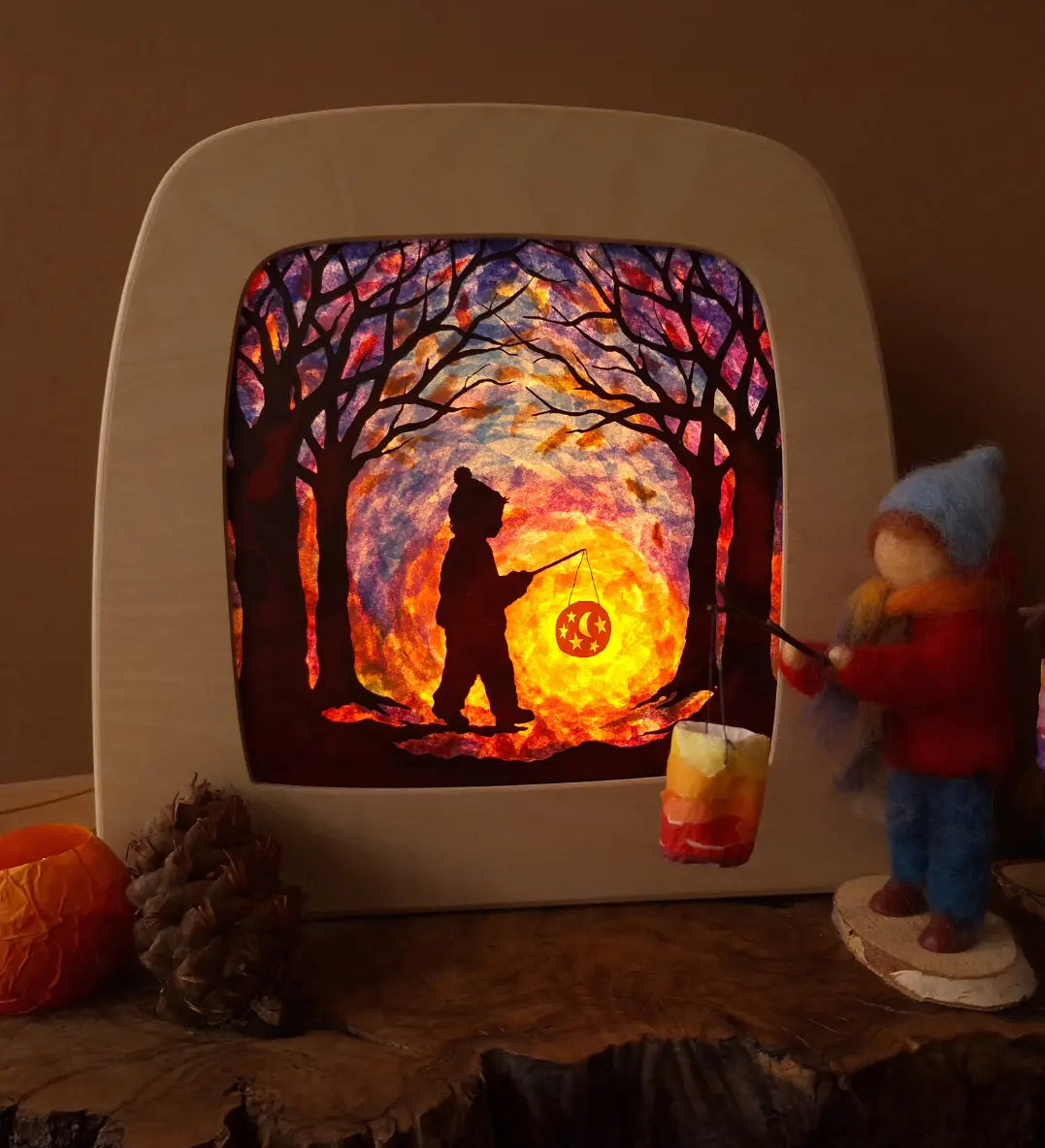 Toverlux DIY kit creation featuring a multicoloured sky with a silhouette of a child carrying a lantern through a forest in a parade displayed in a lit up magic lamp.