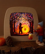 Toverlux DIY kit creation featuring a multicoloured sky with a silhouette of a child carrying a lantern through a forest in a parade displayed in a lit up magic lamp.