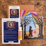 Toverlux Martinmas Silhouette DIY craft kit content laid out on a wooden surface. The kit includes silhouette panel with child carrying a lantern through a forest design, 20 sheets of coloured paper, paint brush, mod podge glue sealer and a step by step instruction guide booklet.