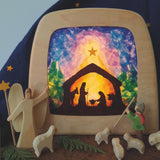 A Toverlux DIY Transparencies with  Winter nativity artwork shown in a wooden magic lamp. Ostheimer wooden toys have been placed in front of it.