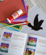 Contents of the Toverlux Spring dove DIY silhouette transparency craft kit featuring a Vogel Geluk design. The kit includes silhouette panel with dove design, 20 sheets of coloured paper, paint brush, mod podge glue sealer and a step by step instruction guide.