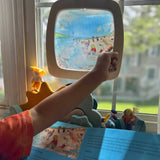 Toverlux Edulux watercycles silhouette featuring Stephanie Green's Estuary artwork shown in a wooden magic window frame. A Grimm's weather set has been set up on the windowsill underneath. A child's hand can be seen pointing at some of the details in the artwork.
This silhouette is part of a wide range of Toverlux silhouettes available here at Babipur. 