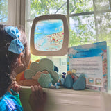 Toverlux Edulux watercycles silhouette featuring Stephanie Green's Estuary artwork shown in a wooden magic window frame. A Grimm's weather set has been set up on the windowsill underneath and a child is looking at the artwork.
This silhouette is part of a wide range of Toverlux silhouettes available here at Babipur. 