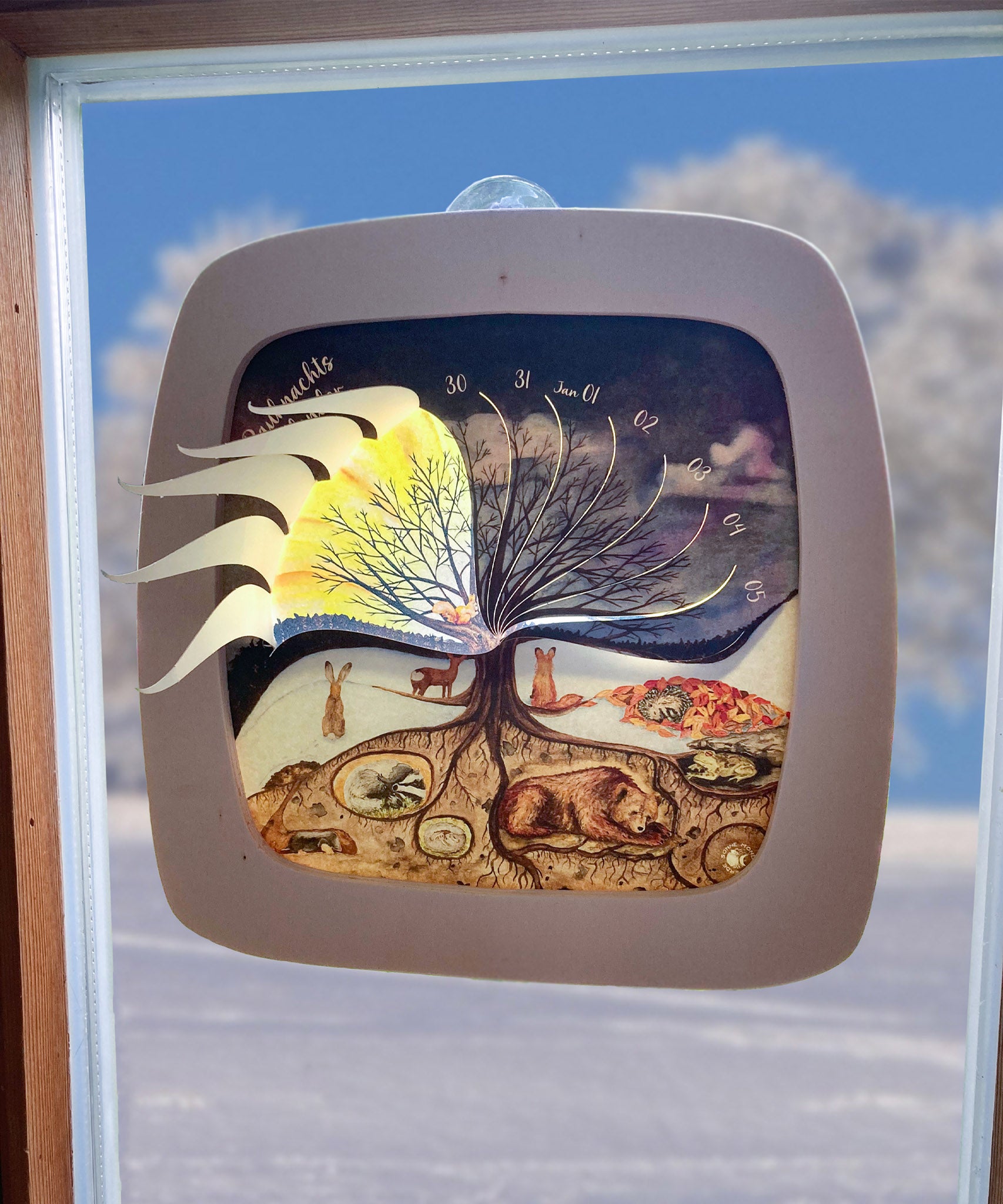 The Toverlux 12 holy nights silhouette inside a magic frame hanging on a window showing the little doors open revealing the illustration inside. Silhouette and frame are both available at Babipur