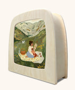 A Toverlux lamp pictured with a silhouette inside featuring artwork from artist Tijana Draws titles picnic on a plain background. 