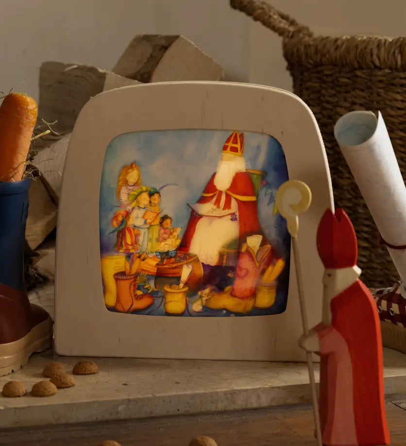 Toverlux layered light silhouette with Saint Nicholas Christmas artwork by Anne Illustrates displayed in a lit magic lamp with an Ostheimer father Christmas Waldorf figure placed in front.