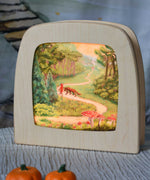 Toverlux Kapitein Kalk - Little Red Riding Hood Silhouette placed in a magic lamp placed on a table. A beautiful illustration featuring little red hood walking through a forest next to a wolf. 
A range of Toverlux silhouettes, lamps and accessories are available at Babipur.