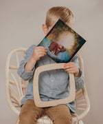 A child inserting a silhouette inside the  Toverlux Artisan Magic Window Frame available at Babipur. 