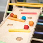 Close up of wooden balls rolling down a ball run made with the Triclimb wooden Miri slide and pastel Miri sticks