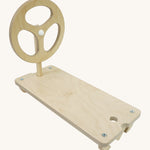 A Triclimb wooden Arben wheel attatched onto a Arben base that can be hooked on the top rungs of a Triclimb pikler climbing frame