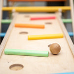 Close up of wooden balls rolling down a ball run made with the Triclimb wooden Miri slide and pastel Miri sticks