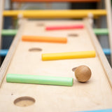Close up of wooden balls rolling down a ball run made with the Triclimb wooden Miri slide and pastel Miri sticks