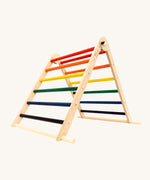 Triclimb folding wooden pikler climbing frame with rainbow inspired coloured rungs including purple, blue, green, yellow, orange and red. Features longer natural coloured rungs on the bottom as a base. 