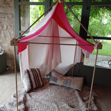 A cosy tent setup made from the Trigonos wooden big start set showing a pink cloth on top of the frame standing on a concrete surface