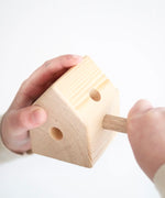 Child hand assembling a wooden Trigonos pole in a triangular corner corner block