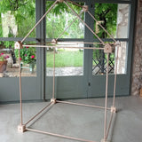 Trigonos big start set showing a tent made up from wooden poles and corner blocks standing on a concrete surface