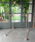 Trigonos big start set showing a tent made up from wooden poles and corner blocks standing on a concrete surface